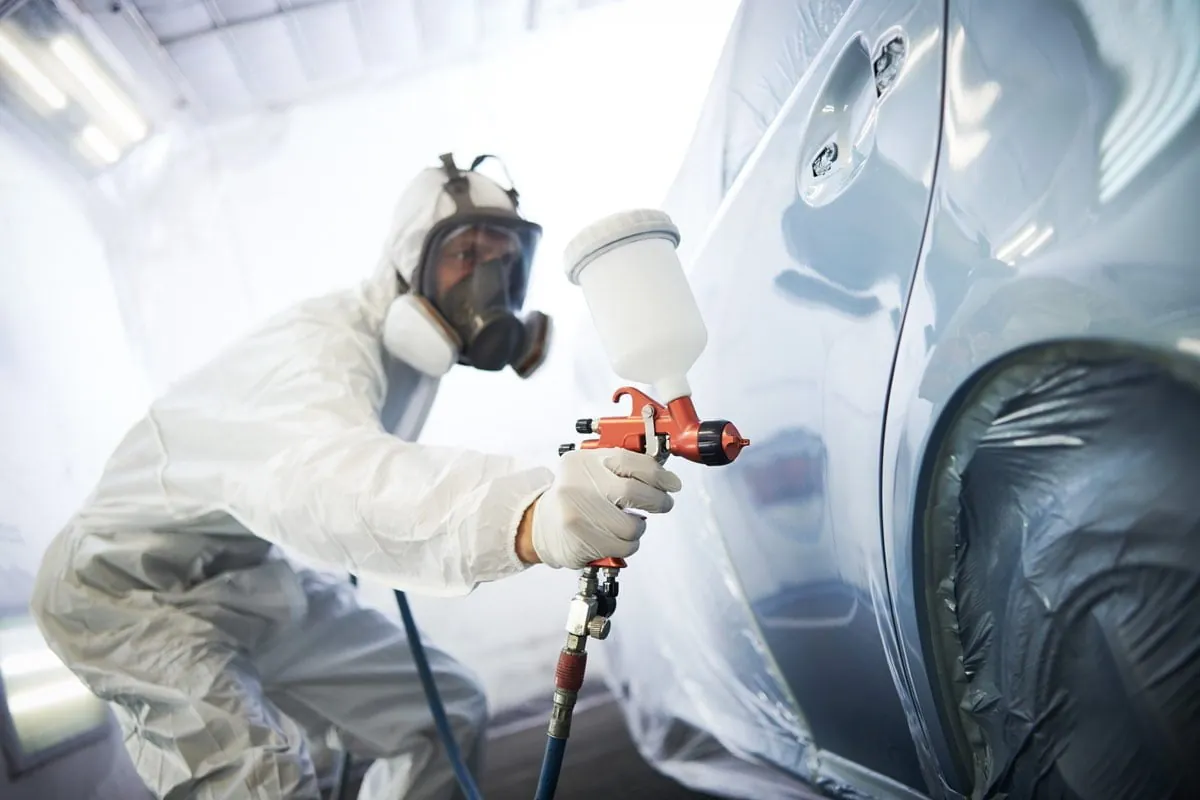 A painter in a spray booth refinishing a vehicle panel