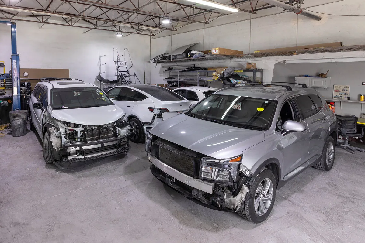 Damaged vehicles waiting for repair inside a collision shop